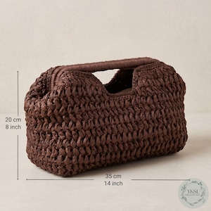 May include: A brown woven handbag with a handle. The bag is 35 cm long and 20 cm high. The bag has a rectangular shape with a woven texture. The handle is a darker shade of brown.