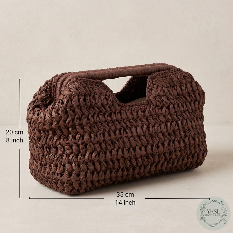 May include: A brown woven handbag with a handle. The bag is 35 cm long and 20 cm high. The bag has a rectangular shape with a woven texture. The handle is a darker shade of brown.