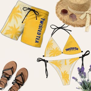 Puede incluir: Un conjunto de bikini y pantalón corto de baño amarillo y crema con diseños de palmeras. La parte superior del bikini y el pantalón corto de baño tienen el texto "Twisted Tea" en azul. Un sombrero de paja, gafas de sol y sandalias completan el conjunto temático de playa.