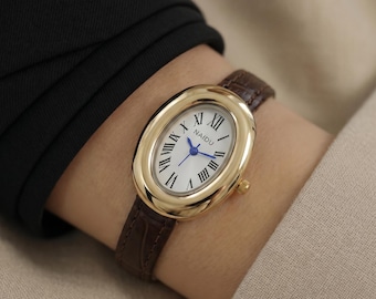 Reloj ovalado tono dorado, estilo vintage para mujer, correa de cuero marrón, esfera con números romanos.