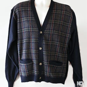 May include: A button-down cardigan sweater with a plaid pattern in shades of navy, green, and burgundy. The sleeves and trim are solid navy blue. The sweater has two front pockets and is displayed on a mannequin.