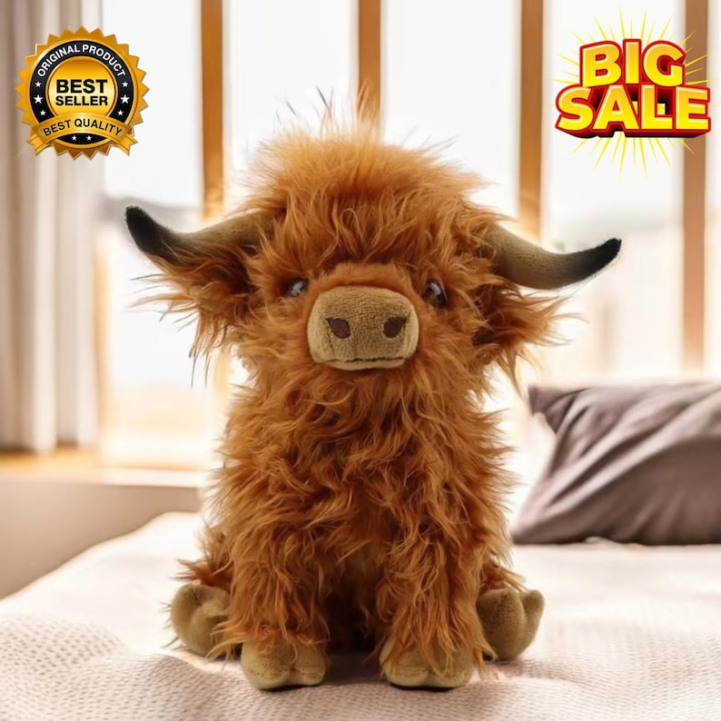 Puede incluir: Un peluche de vaca de las Tierras Altas con pelaje marr&oacute;n y lanudo, cuernos negros y una cara detallada. El juguete est&aacute; sentado en una cama. La imagen tambi&eacute;n incluye una insignia de "Best Seller".