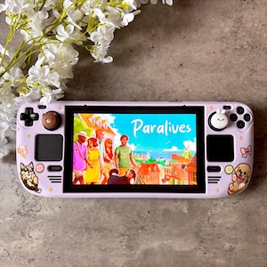 May include: A light purple handheld gaming console featuring a screen displaying the game Paralives. The device is decorated with small stickers of a dog, a puppy, and bows, and includes brown bear and white rabbit thumbstick covers on the joysticks.