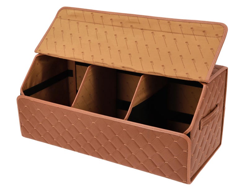 Op de afbeelding: Een bruine, gewatteerde kofferbakorganizer met een scharnierend deksel. De binnenkant is verdeeld in drie compartimenten. Het deksel en de binnenvoering hebben een herhalend patroon. Een handvat is zichtbaar aan de zijkant.