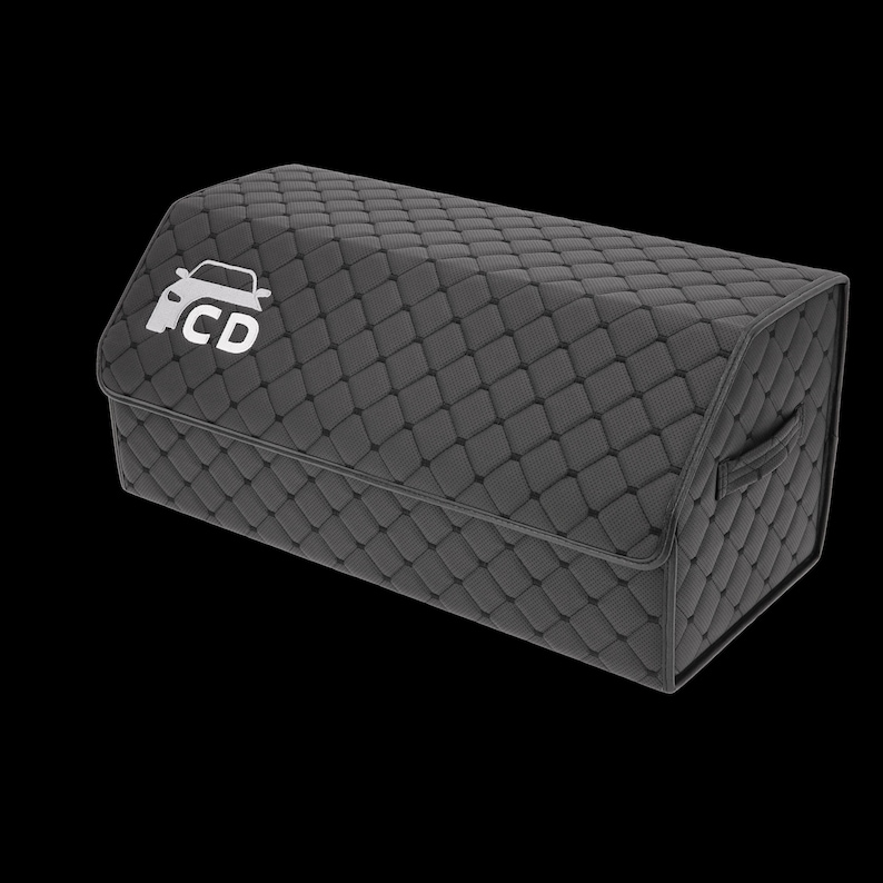 May include: A dark gray, quilted car trunk organizer with a rectangular shape. The organizer features a white car logo with the letters "CD" on the front flap and a handle on the side. The stitching creates a diamond pattern.