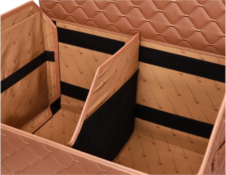 May include: A tan, multi-compartment car organizer with a quilted exterior. The interior features multiple sections with black velcro straps for securing items. The organizer is designed to keep a car's interior tidy and organized.