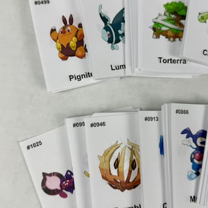 May include: A collection of white rectangular cards featuring colorful illustrations of various creatures. Each card displays a unique identification number, such as #0499, #0457, #0389, #1025, #0946, #0913, and #0866, along with names like Pignite, Torterra, and Bramblin.