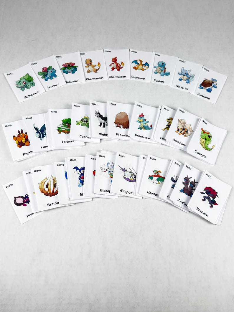 May include: A collection of white rectangular trading cards featuring various colorful cartoon creature illustrations. Each card displays a unique character, a corresponding identification number, and a name printed in black text below the image.