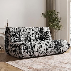 May include: A modern, low-profile sofa with a black and white abstract pattern. The sofa has a rounded shape and a textured appearance, suitable for a living room or lounge area. The design is contemporary and stylish.