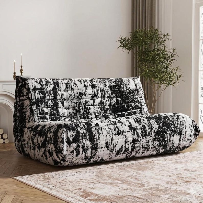 May include: A modern, low-profile sofa with a black and white abstract pattern. The sofa has a rounded shape and a textured appearance, suitable for a living room or lounge area. The design is contemporary and stylish.