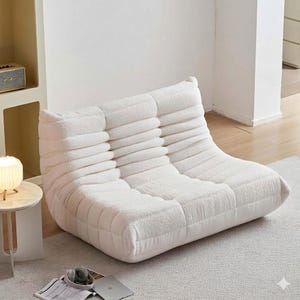 May include: A white, low-profile, modular sofa with a textured, ribbed design. The sofa is made of a soft, plush material and is designed for comfortable seating. The modern, minimalist design is suitable for a living room or lounge area.