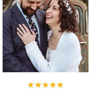 Puede incluir: Una pareja se sonr&iacute;e, la mujer lleva una estola de punto blanco sobre su vestido de novia. La estola tiene un delicado encaje. La pareja est&aacute; de pie frente a un cami&oacute;n vintage.