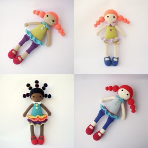 May include: Four handmade crochet dolls with different skin tones and hair colors. Each doll wears a unique outfit, including dresses, leggings, and shoes. The dolls have button details and are arranged on a white background.
