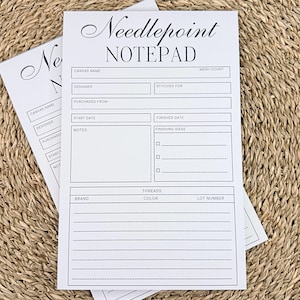May include: Two white Needlepoint Notepad pads with black text. The top pad has the title "Needlepoint NOTEPAD" in elegant script. The notepad includes sections for canvas name, designer, start date, and threads.