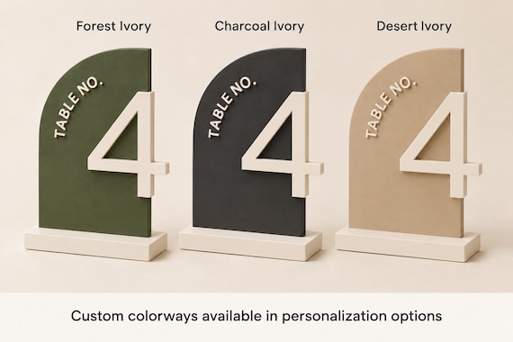 Three labeled half-arch Table No. 4 signs: Forest Ivory, Charcoal Ivory, and Desert Ivory, with a footer about Custom colorways in personalization options.