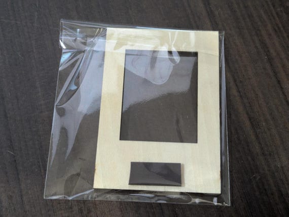 Back view of a packaged birch mini photo frame showing the attached round magnet and protective bag.
