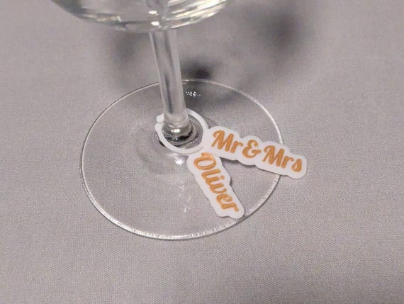 Personalized Mr and Mrs and Oliver wine glass charms shown close up on clear stemware.