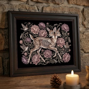 May include: A framed wall art print featuring a two-headed fawn with a visible ribcage skeleton, surrounded by mauve-colored peonies and small birds on a black background. The artwork is enclosed in a dark brown wooden frame with a beveled edge.