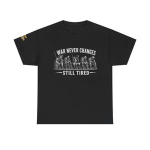 Könnte beinhalten: Schwarzes T-Shirt mit einem weißen Grafikdesign. Das Design zeigt den Text "WAR NEVER CHANGES" über einer Illustration von Soldaten und den Text "STILL TIRED" darunter.