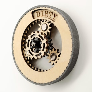 May include: A wooden round sign with a gray outer ring and a gear mechanism inside. The sign says "DIRTY" in a wood-burned font.