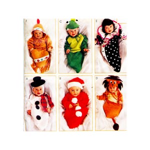 May include: A collection of six baby costumes, including a Native American, frog, clown, snowman, Santa, and lion. Each costume is brightly colored and designed for infants. The costumes are displayed on a white background.