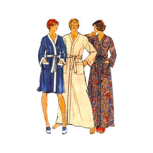 May include: Three robes are displayed: a knee-length navy blue robe with white trim, a full-length cream-colored robe with a tie waist, and a full-length robe featuring a vibrant, multi-colored paisley pattern with long sleeves and a tie waist.