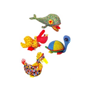 May include: A collection of handmade fabric animal toys, including a whale, duck, turtle, and another duck. The toys feature colorful floral and patchwork patterns in red, yellow, blue, and green. Each toy has unique details like a yellow beak or a red tongue.