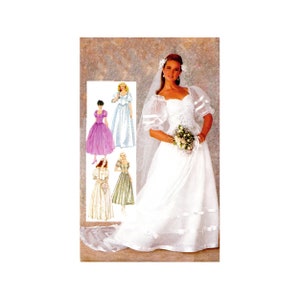 May include: A white wedding dress with a sweetheart neckline and puff sleeves. The dress has a full skirt and a long train. The bride is wearing a veil and holding a bouquet of flowers.
