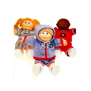 Peut inclure: Trois poupées Cabbage Patch Kids, l'une avec des cheveux blonds portant un sweat à capuche bleu et un short rouge, l'autre avec des cheveux roux portant une chemise rayée et une jupe, et la dernière avec une peau brune portant une chemise rouge et un pantalon.