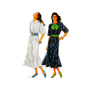 May include: Two women wearing long dresses. The woman on the left is wearing a white dress with black polka dots and a blue belt. The woman on the right is wearing a black dress with a green bow and a green belt.