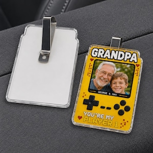 May include: A yellow rectangular acrylic air freshener with a metal clip, featuring a pixelated game console design. The screen displays a photo of an older man and a young boy with the text GRANDPA, GEORGE & MAX, and YOU'RE MY PLAYER 1.