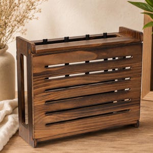 May include: A rectangular dark brown wooden knife block featuring a slatted front design with horizontal openings. The structure has vertical side panels and a top section with black inserts for holding kitchen knives securely in place.