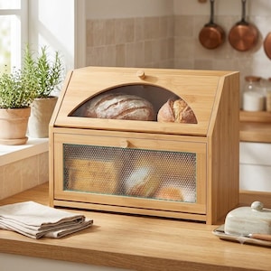 May include: A two-tier bamboo bread box with a light wood finish. The top section features a curved glass window displaying two loaves of bread, while the bottom section has a textured, semi-opaque glass drop-down door with a small wooden knob.