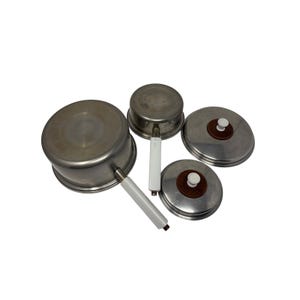May include: A set of vintage stainless steel pots and pans with white handles and lids. The set includes two pots and two lids with brown and white accents. The cookware is arranged on a white background.