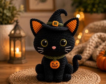 May include: A black crocheted cat figurine wearing a pointed black witch hat with an orange band and buckle. The cat has large green eyes, a pink nose, white embroidered whiskers, and a green collar featuring a small orange jack-o'-lantern charm.