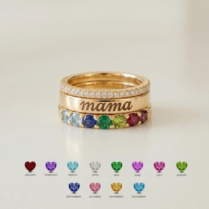 May include: A stack of three gold rings. The top ring features a row of small clear stones. The middle ring is a smooth gold band engraved with the word mama. The bottom ring contains a row of multi-colored round stones representing birthstones.