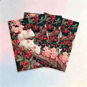 Puede incluir: Impresiones artísticas que muestran una ilustración caprichosa de ratones blancos durmiendo en una rama de árbol entre cerezas rojas y flores rosas. El fondo es de color verde oscuro, creando un contraste llamativo.