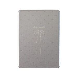 May include: A rectangular, silver-colored tin with a decorative pattern of small floral designs. The words "dear reader" are written in a delicate script above a simple bow illustration with long, flowing ribbons.
