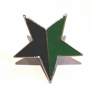 Puede incluir: Un pin de esmalte negro y verde en forma de estrella de cinco puntas.