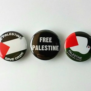 Könnte beinhalten: Drei runde Buttons mit politischen Botschaften über Palästina. Der erste Button ist schwarz mit weißem Text, der "FREE PALESTINE" lautet. Der zweite Button hat einen weißen Hintergrund mit einem roten Dreieck und schwarzem Text, der "FREE PALESTINE! SAVE GAZA!" lautet. Der dritte Button hat einen grünen Hintergrund mit einer weißen Taube und rotem Text, der "PALESTINE A HOMELAND DENIED" lautet.