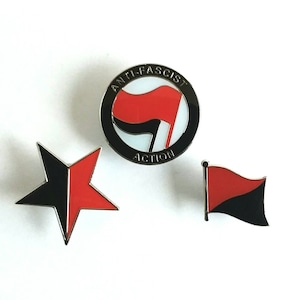 Pode incluir: Três pinos de esmalte com símbolos antifascistas. O primeiro pino é um círculo com o texto "Anti-Fascist Action" e uma bandeira vermelha e preta. O segundo pino é uma estrela vermelha e preta. O terceiro pino é uma bandeira vermelha e preta.
