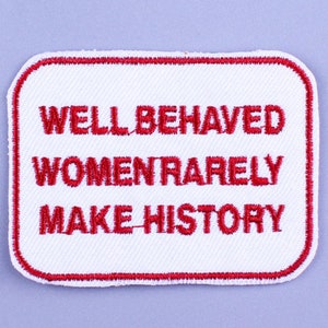 Puede incluir: Parche blanco bordado con costuras rojas y el texto "WELL BEHAVED WOMEN RARELY MAKE HISTORY".