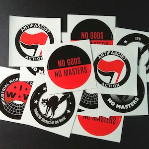 May include: A collection of black and red stickers with various slogans, including "Anti-Fascist Action", "No Gods No Masters", and "Industrial Workers of the World".
