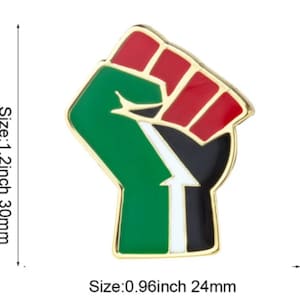 May include: A gold-coloured metal pin in the shape of a raised fist. The fist is coloured red, black, green, and white. The pin is 1.2 inches or 30 mm in size.