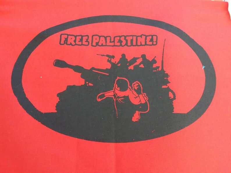 May include: A red t-shirt with a black oval graphic. The graphic features a tank, soldiers, and the text "FREE PALESTINE!"