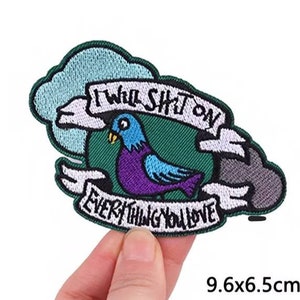 May include: An embroidered iron-on patch featuring a cartoon bird and the text "I will shit on everything you love". The patch is green, blue, and purple and measures 9.6 by 6.5 centimetres.