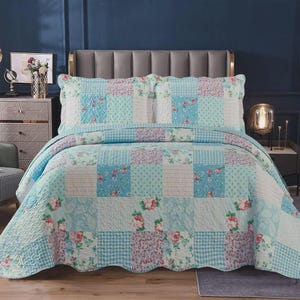 May include: A patchwork quilt and two pillowcases in shades of blue, white, and pink. The quilt features floral prints, polka dots, and gingham checks. The bedding is arranged on a bed with a grey headboard.
