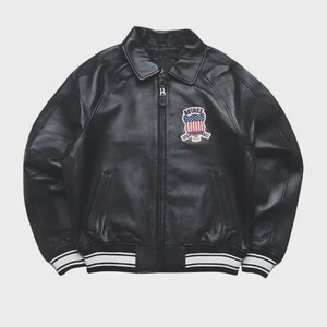 May include: Black leather bomber jacket with a zip-up front, collar, and a patch on the chest. The patch features a design with red, white, and blue colors. The jacket has white and black striped cuffs and hem.