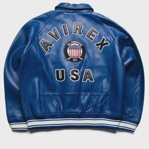 May include: A vibrant blue leather jacket with the word "AVIREX" arched across the upper back. Below, the word "USA" is displayed. A circular patch with the words "ALL AMERICANS ESTABLISHED 1975" and a US flag is centered. The jacket has white and blue striped trim.