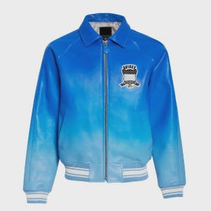May include: A blue leather jacket with a gradient effect, transitioning from a deep blue at the top to a lighter shade at the bottom. Features a collar, zipper closure, and a patch on the chest with the text "AVIREX". The jacket has white and blue striped cuffs and hem.